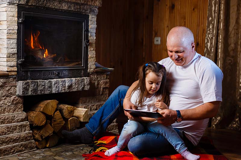  grandfather and little girl reading in front of fireplace